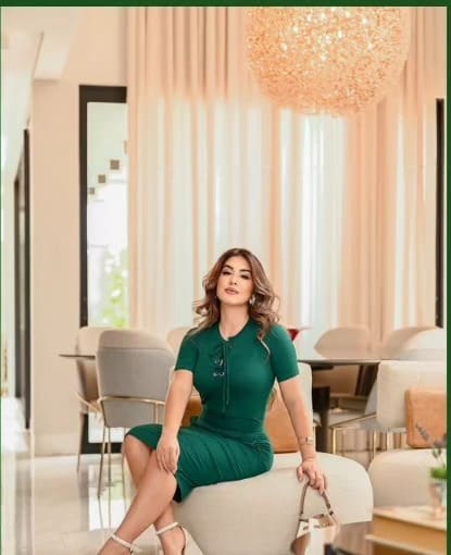 Cliente sentada usando conjunto verde-esmeralda da Perfeitta, com bolsa clara ao lado.